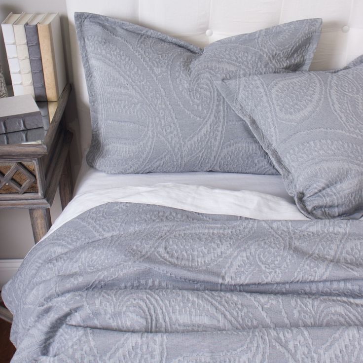 a bed with two pillows on top of it next to a night stand and nightstand