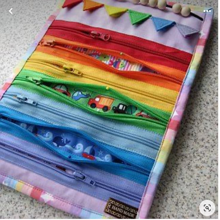 there are many different zippers on the table and one is multicolored with cars