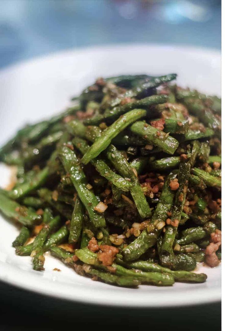 a white plate topped with green beans covered in seasoning