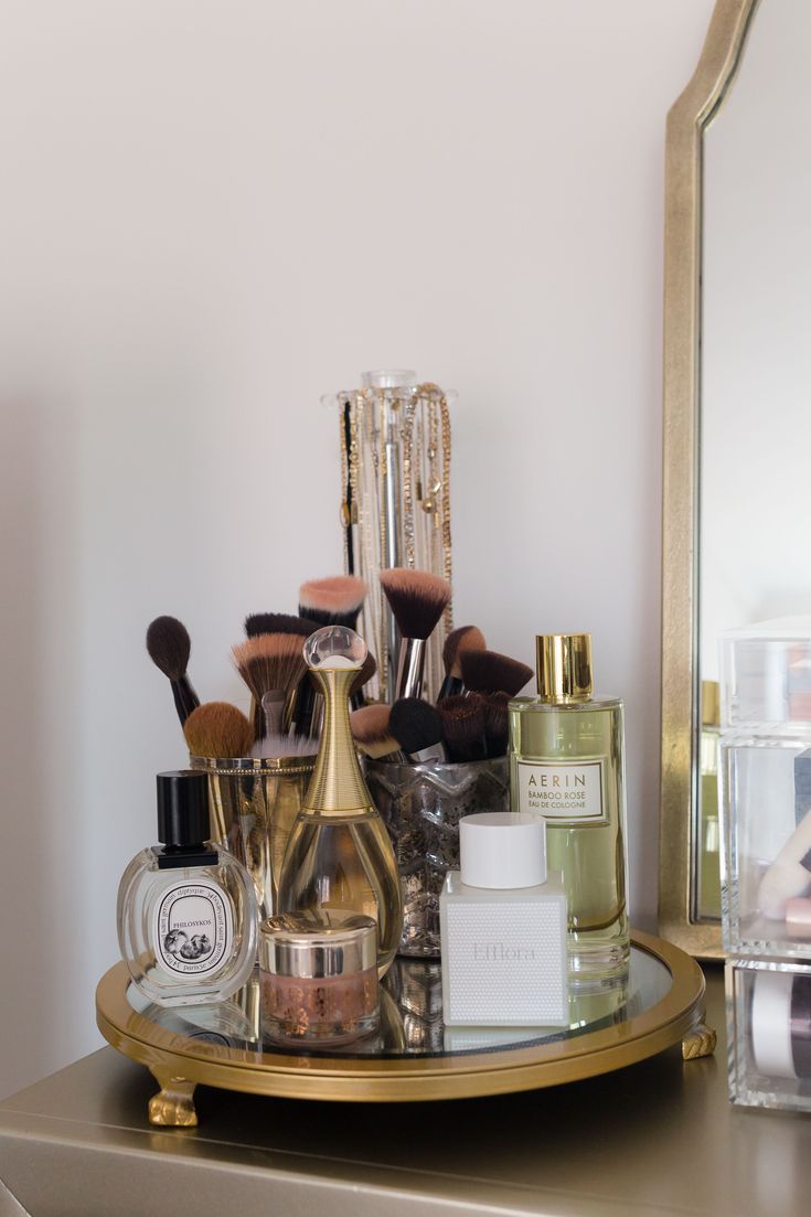 a gold tray with cosmetics and makeup brushes on it