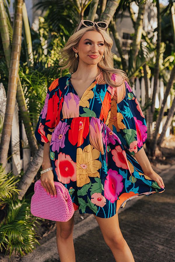 - Embrace floral vibes with this flowy dress! - Soft material with a pink, red, orange, yellow, blue, and green hued floral print - A built-in lining - A v-cut neckline with a tie detail - Long, loose sleeves with elastic cuffs - A lightweight silhouette that ends in a mini dress length hemline Colorful Floral Print V-neck Dress, Vibrant Floral Print V-neck Mini Dress, Multicolor Print V-neck Summer Dress, Multicolor V-neck Floral Dress With Vibrant Print, Colorful V-neck Vacation Dress, Multicolor Vibrant Print V-neck Dress, Colorful V-neck Mini Dress, Multicolor V-neck Mini Dress With Vibrant Print, Colorful V-neck Dress For Day Out