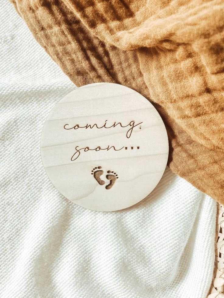 a wooden sign that says, coming soon with a baby's foot on it