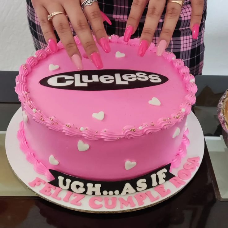 a woman is cutting into a cake with pink frosting and hearts on the side