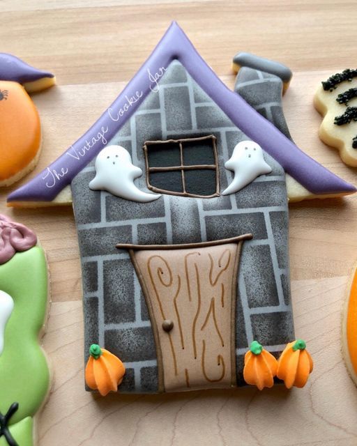 some decorated cookies are sitting on a table with halloween decorations and ghost's around the house