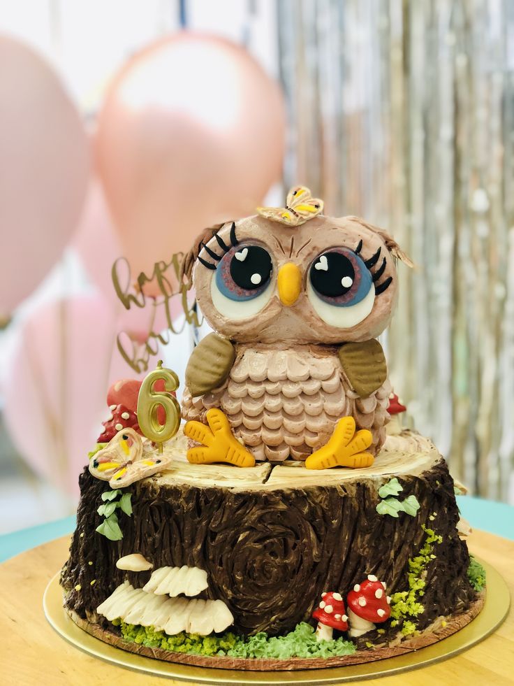 an owl figurine sitting on top of a tree stump with balloons in the background