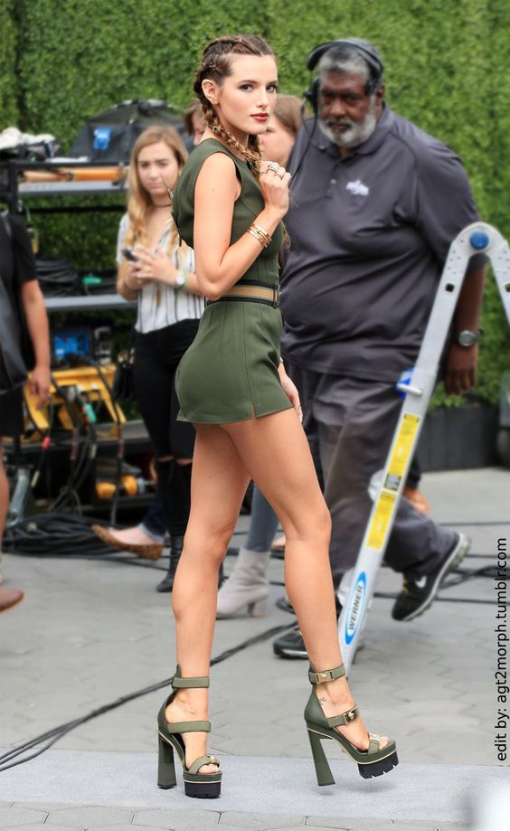 a woman in high heels is walking on the street with other people behind her and another man