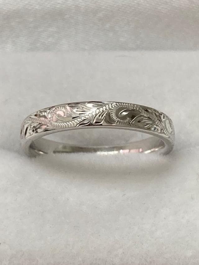 a wedding ring with an intricate design on the front and side, sitting on a white cloth