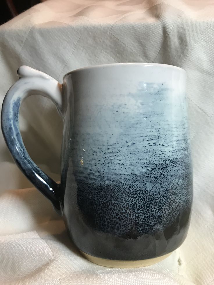 a blue and white mug sitting on top of a bed