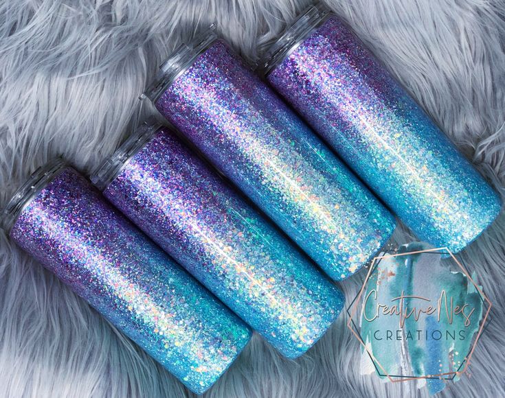 four blue and purple glitter candles sitting on top of a white fur covered floor next to each other