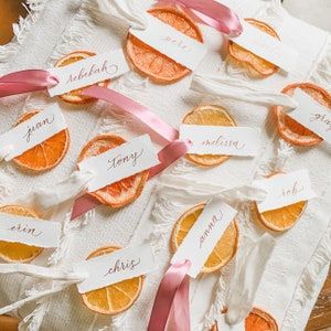 orange slices with ribbons and name tags on them