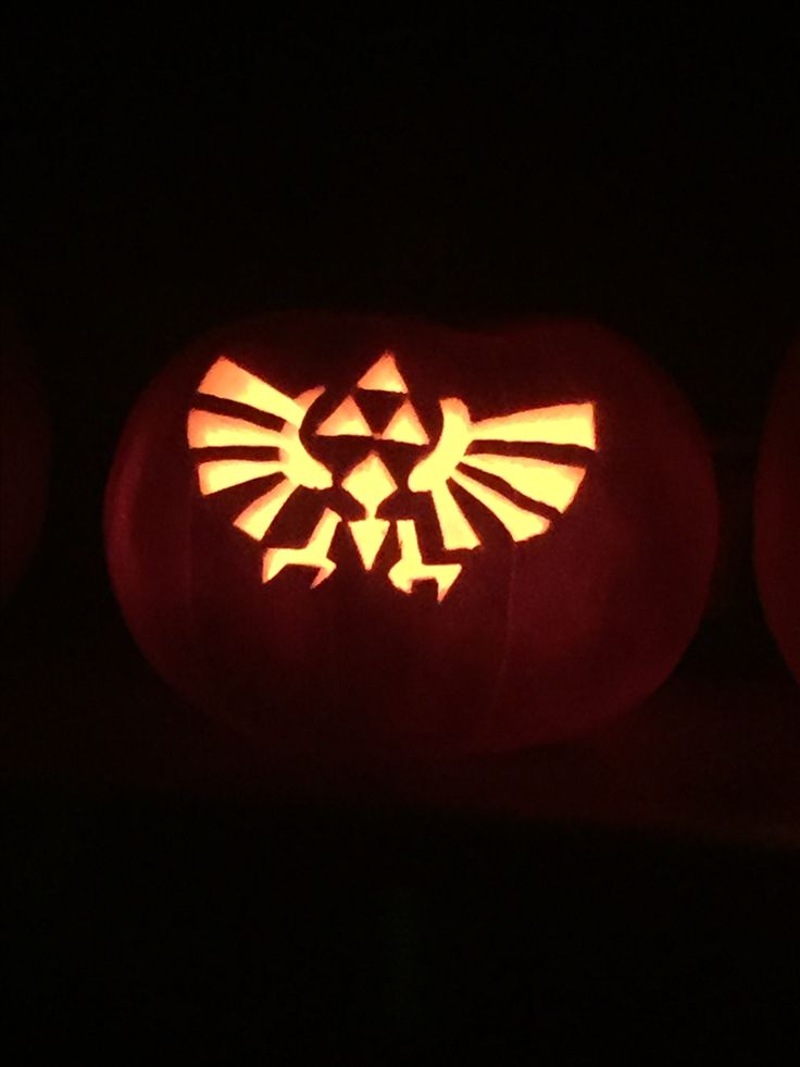 three carved pumpkins with the legend of zelda symbol on them in the dark