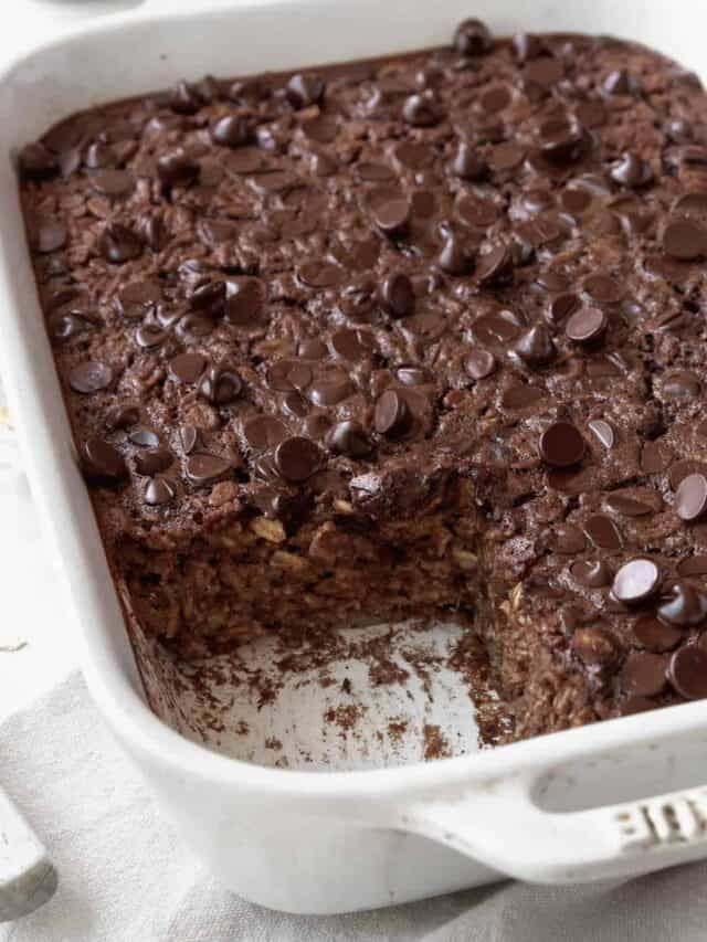 a close up of a cake in a pan with one slice cut out and chocolate chips on top