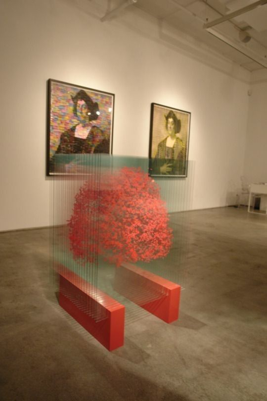 an art gallery with paintings on the wall and two red benches in front of them