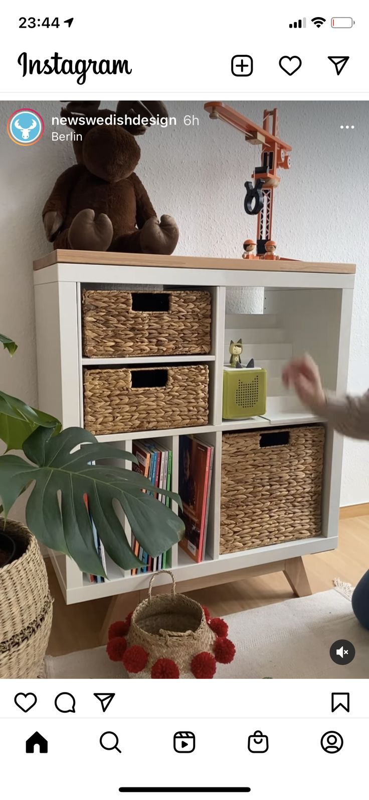 a white bookcase with baskets on it and a stuffed animal in the corner next to it