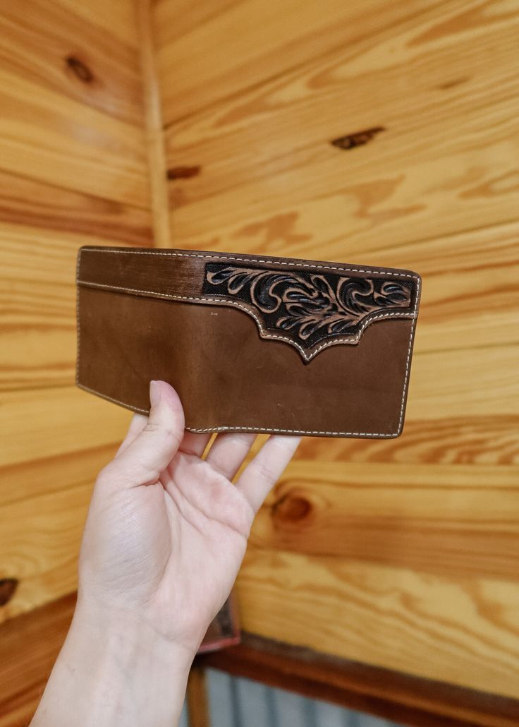 Introducing The Ames Bifold - the ultimate accessory for the stylish and practical individual. Made with high-quality leather and featuring a unique tooled design, this bifold wallet is both functional and fashionable. Keep your essentials organized and secure in a sleek and elegant tan design. Classic Embossed Leather Wallet, Brown Hand-tooled Wallets For Everyday Use, Classic Embossed Bifold Wallets, Brown Embossed Leather Wallet, Hand Tooled Bifold Wallet, Leather Trifold Wallet Hand Tooled For Everyday Use, Leather Hand Tooled Trifold Wallet For Everyday Use, Brown Hand Tooled Trifold Wallet, Hand Tooled Leather Trifold Wallet For Everyday Use