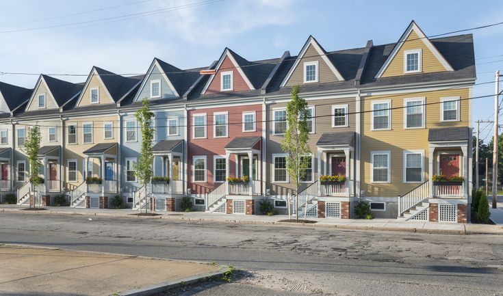 a row of multi - colored townhouses on the side of a street in front of an empty parking lot