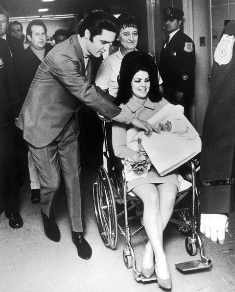 a woman in a wheel chair being handed something by a man in a suit and tie