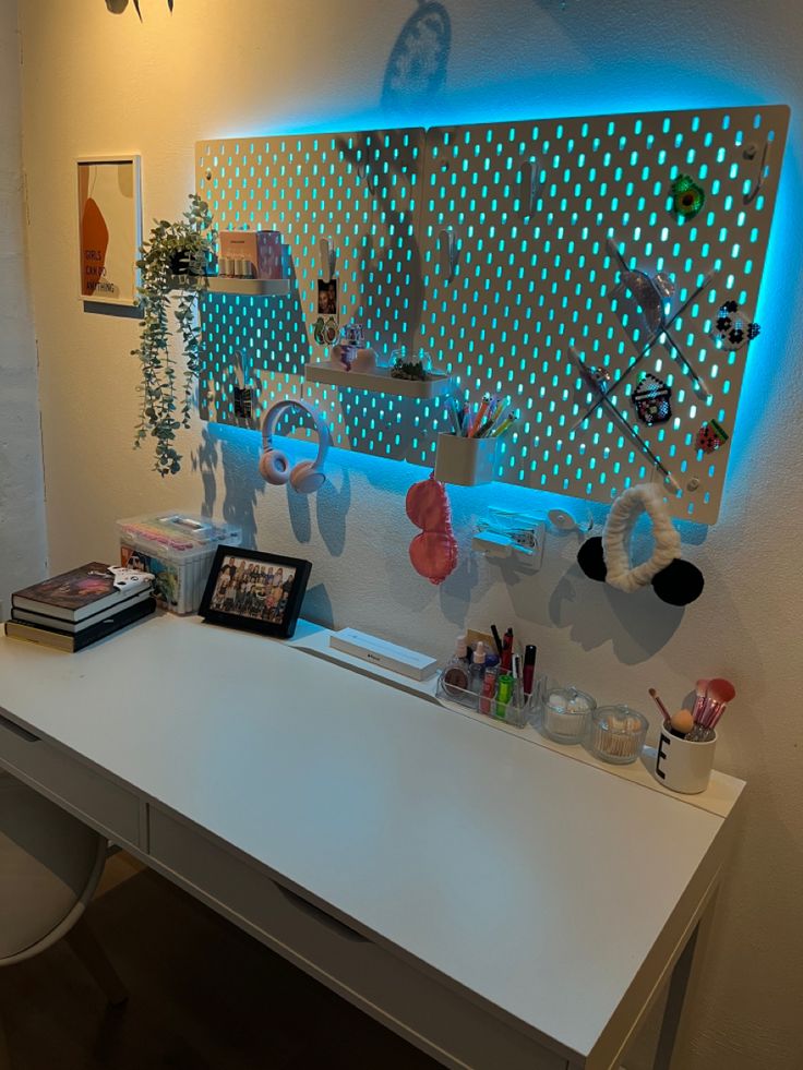 a white desk topped with lots of clutter next to a wall mounted mirror and plant