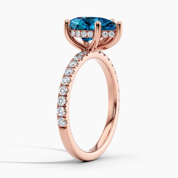 a rose gold engagement ring with an oval cut blue topazte surrounded by diamonds