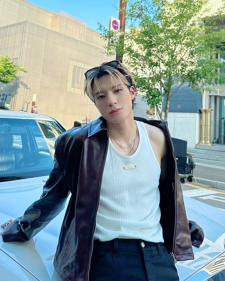 a young man standing next to a parked car