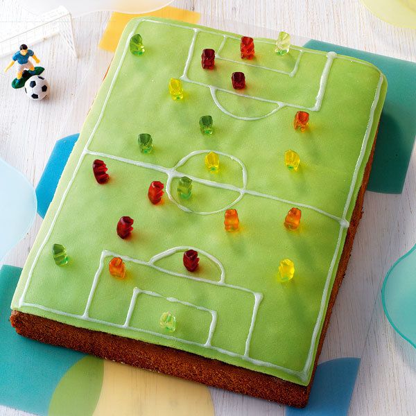 a cake with gummy bears on it and a soccer field frosted in icing