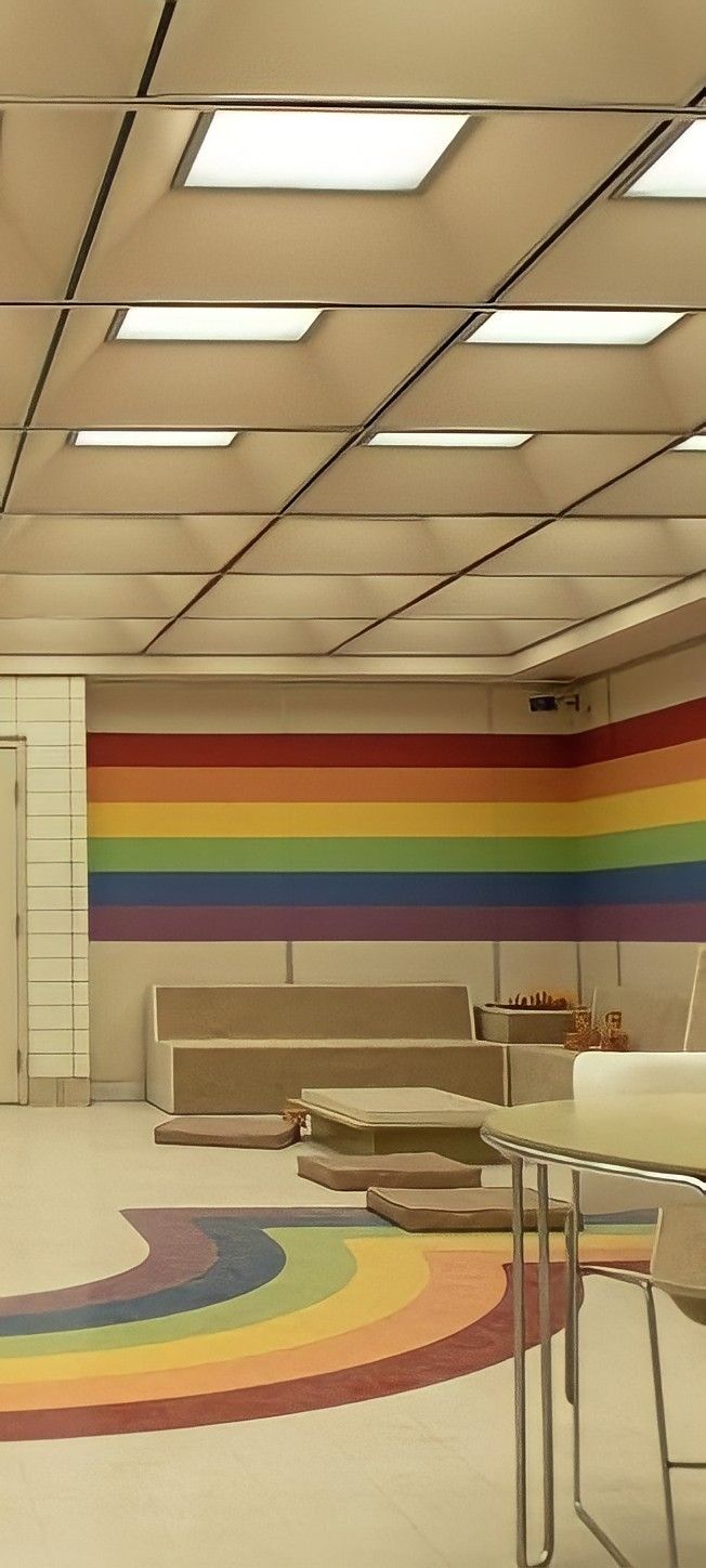 an empty room with rainbow painted on the walls and tables in front of it,