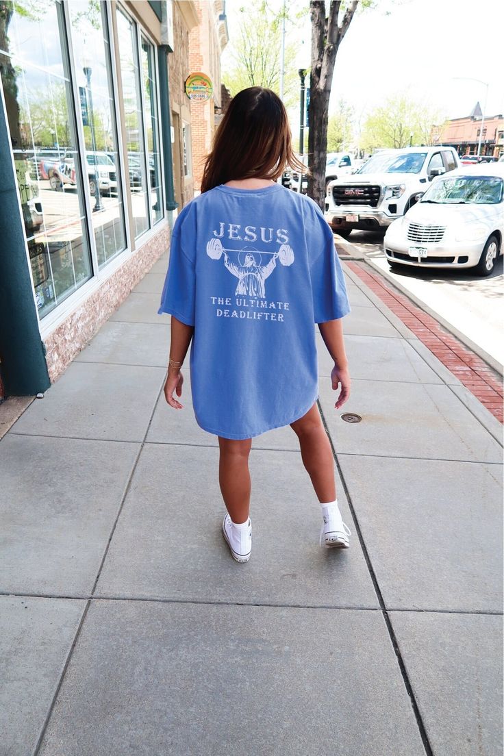 a woman is walking down the sidewalk wearing a blue shirt