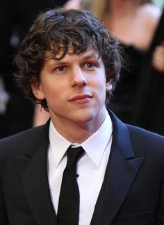 a young man in a suit and tie looking off to the side with other people behind him