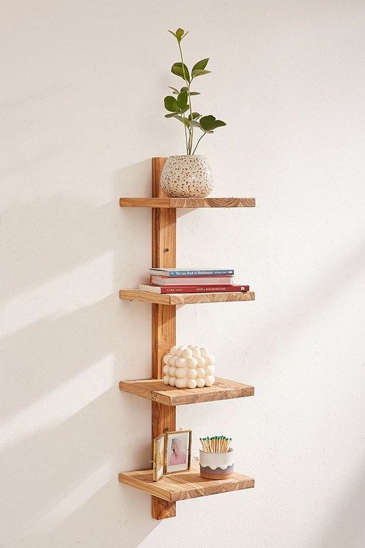 a wooden shelf with three shelves holding books and a potted plant on top of it