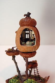 a miniature house made out of wood with a mirror in the middle and trees around it