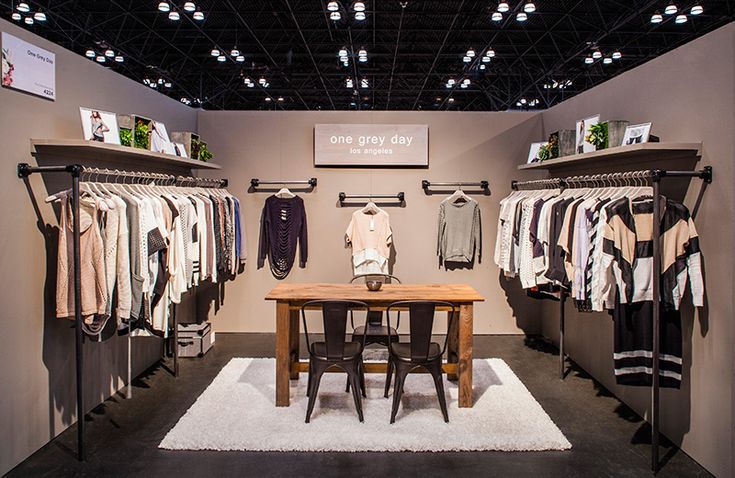 a room filled with lots of clothes on racks next to a table and chairs in front of it