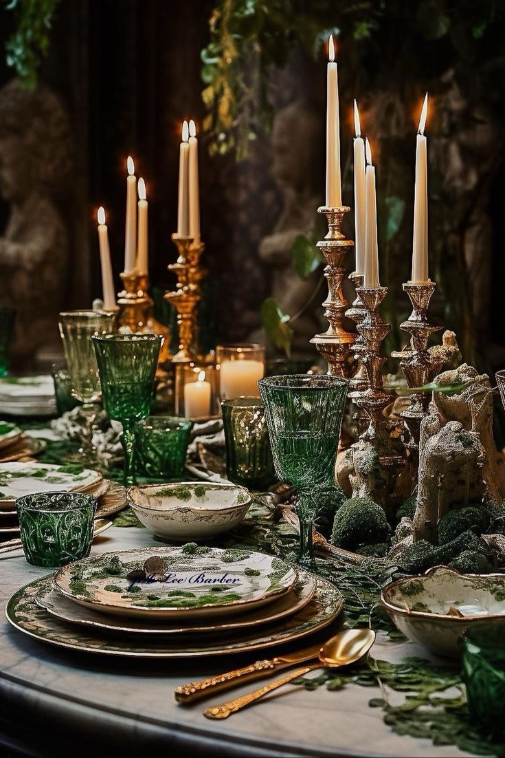 the table is set with candles, dishes and green glassware for dinner guests to enjoy