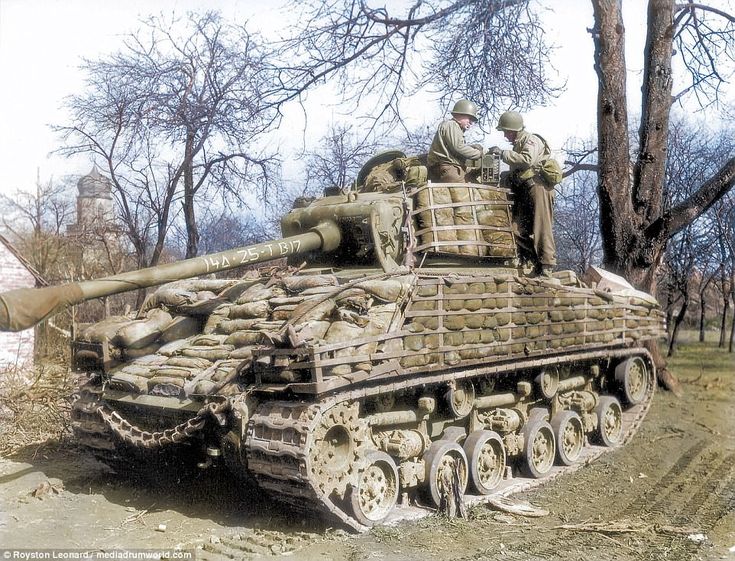 an old tank with soldiers sitting on it's top in the middle of a dirt road