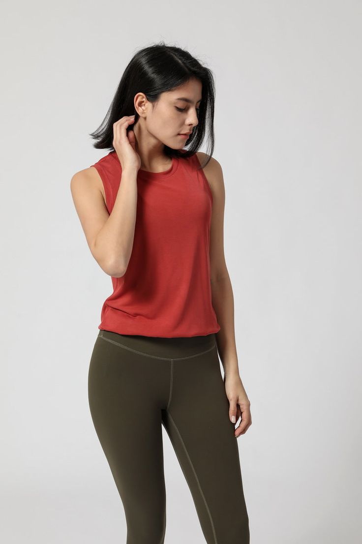 a woman in red top and green leggings talking on her cell phone while standing up