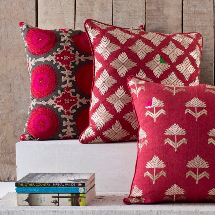 three red pillows sitting on top of a white shelf next to books and a book