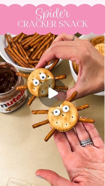 two people holding crackers in the shape of spider faces with pretzels on them