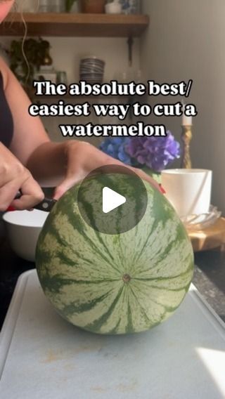 a woman cutting up a large watermelon on top of a kitchen counter with the words, the absolute best easier way to cut a watermelon