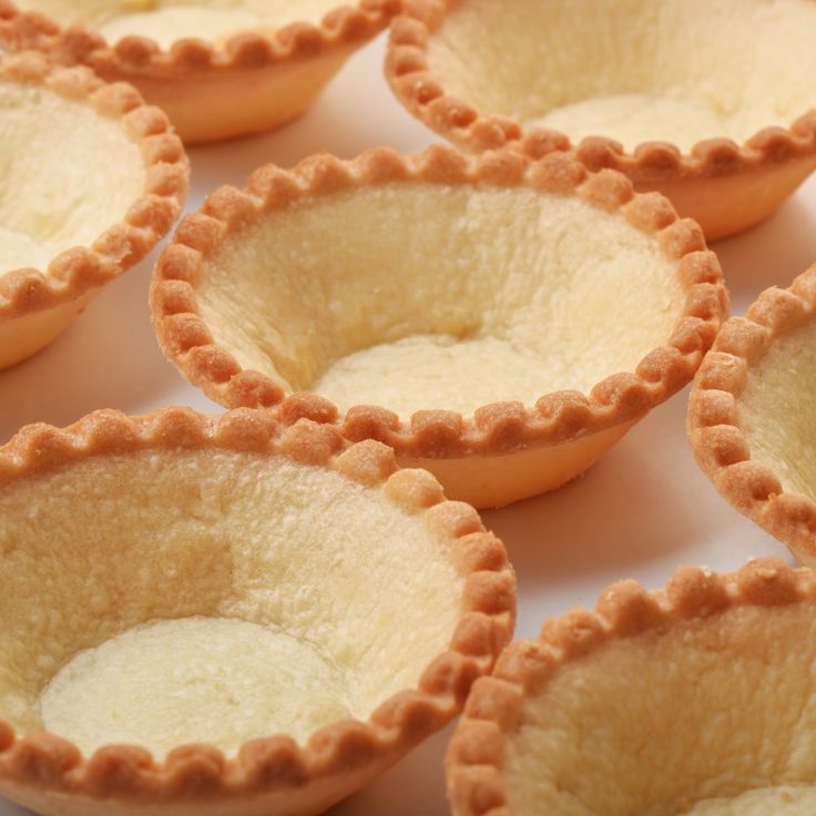 small pies are lined up on a white surface