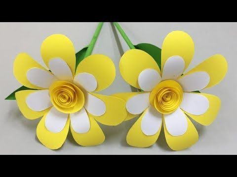 two yellow and white paper flowers sitting on top of each other