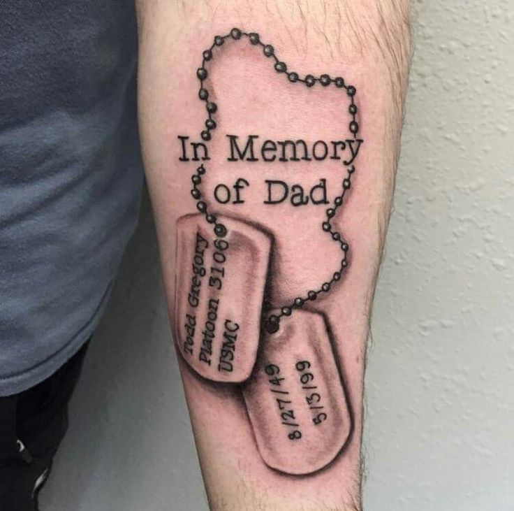 a man with a tattoo on his arm that says in memory of dad and two tags