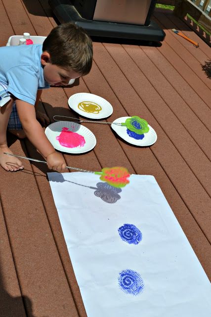 a young boy is painting on paper plates with watercolors in the shape of flowers