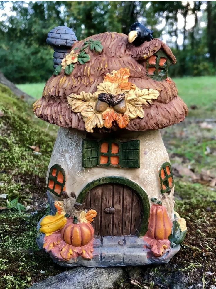 a small house made out of clay with pumpkins and leaves