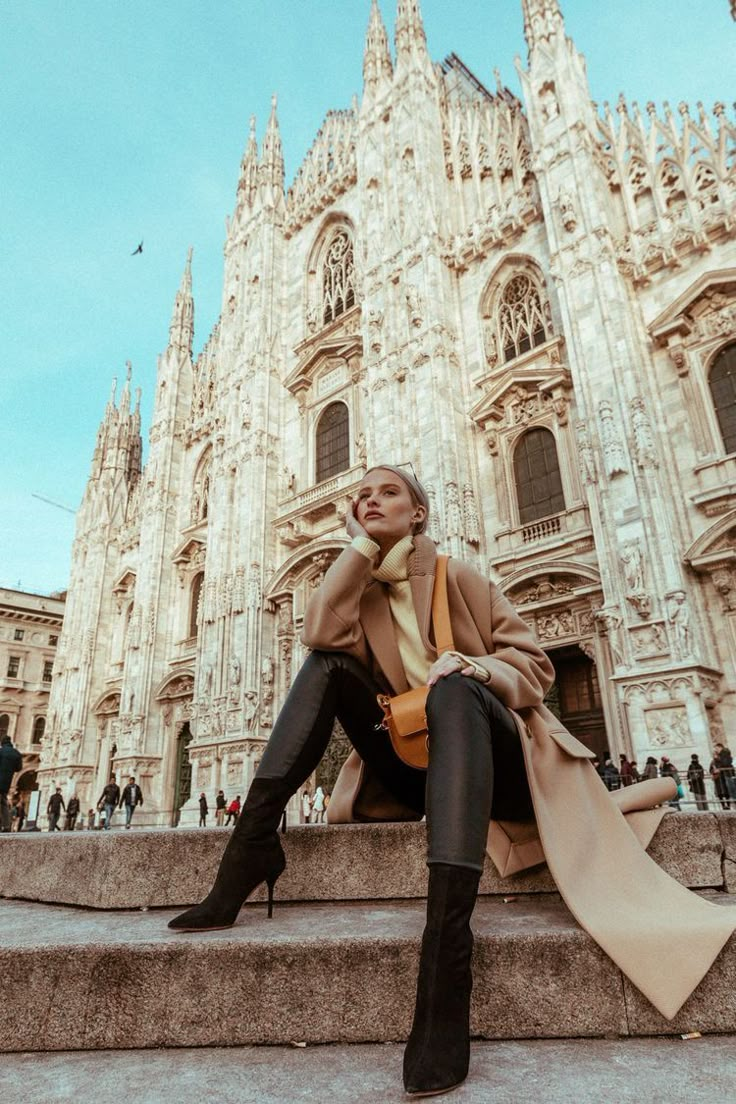 a woman sitting on steps in front of a cathedral