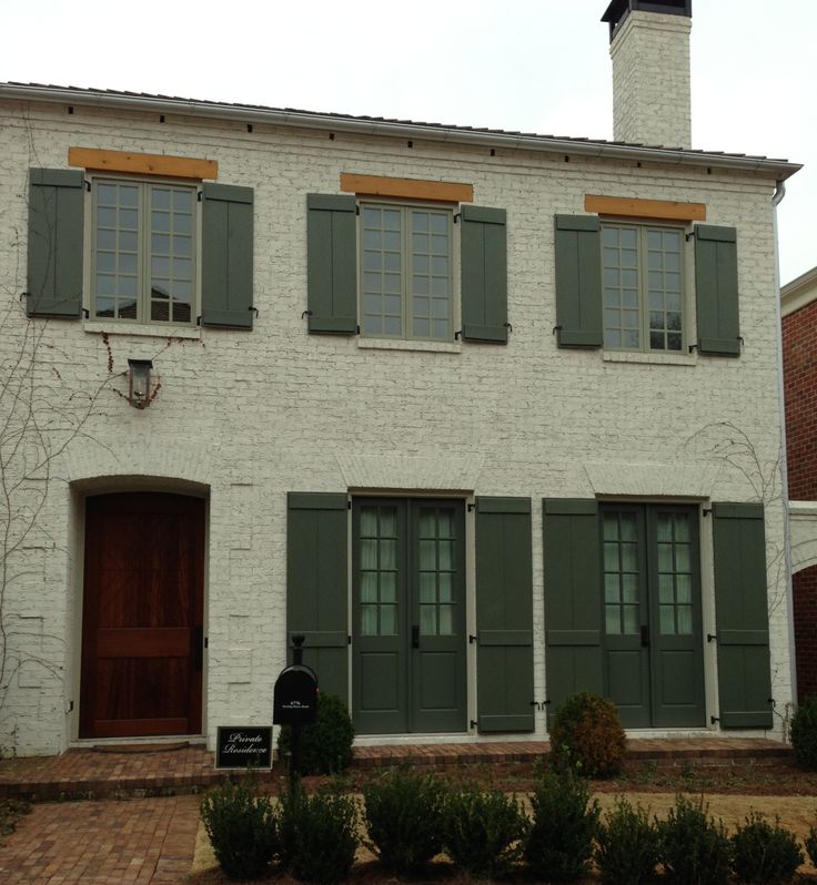 a white brick house with green shutters