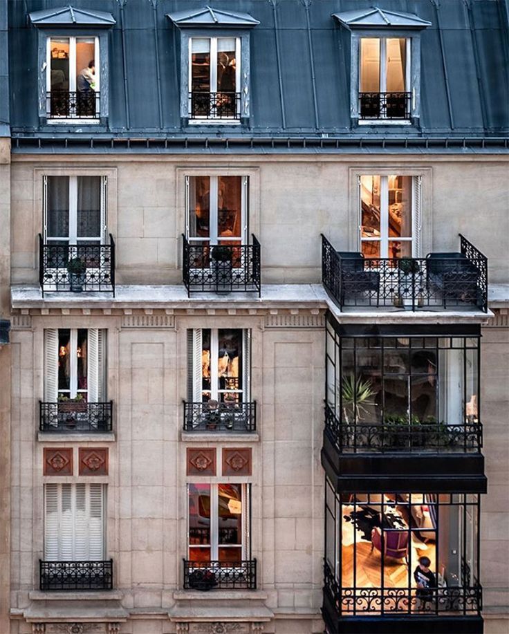 an apartment building with many windows and balconies on the second floor, at night