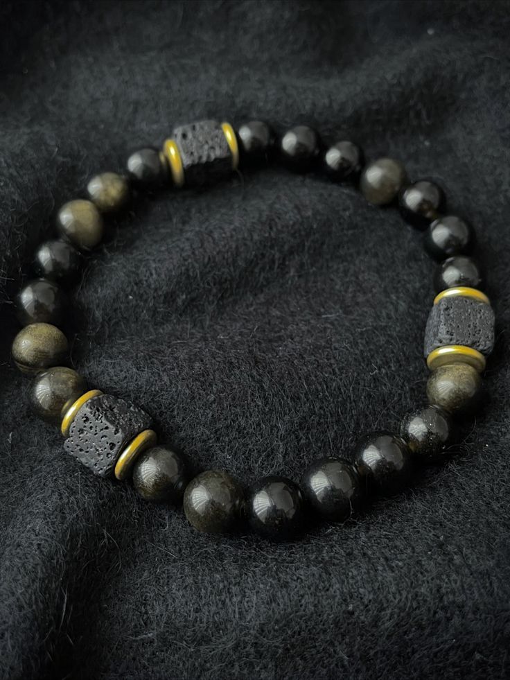 A strongly protective stone, Obsidian is believed to form a shield against negativity and is truth enhancing. It blocks psychic attacks and absorbs negative energies from the environment. There is 1 accent cube Lava Stone bead, which is repeated 3 times for Balance. A grounding stone, Lava Stone is believed to provide stability during times of change and encourages strength and courage. It promotes change where needed for behavioral issues and enhances fertility. Mens Bracelet Black, Balance Bracelet, Lava Bracelet, Thread Jewellery, Miuccia Prada, Men's Bracelet, Bracelet Black, Black Obsidian, Lava Stone