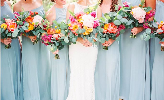 a group of women standing next to each other holding bouquets