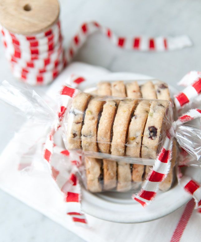 cookies wrapped in plastic on a plate with red and white striped ribbon next to them