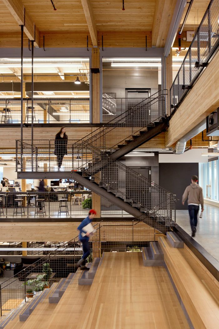 two people are walking up and down the stairs in an office building with wooden floors