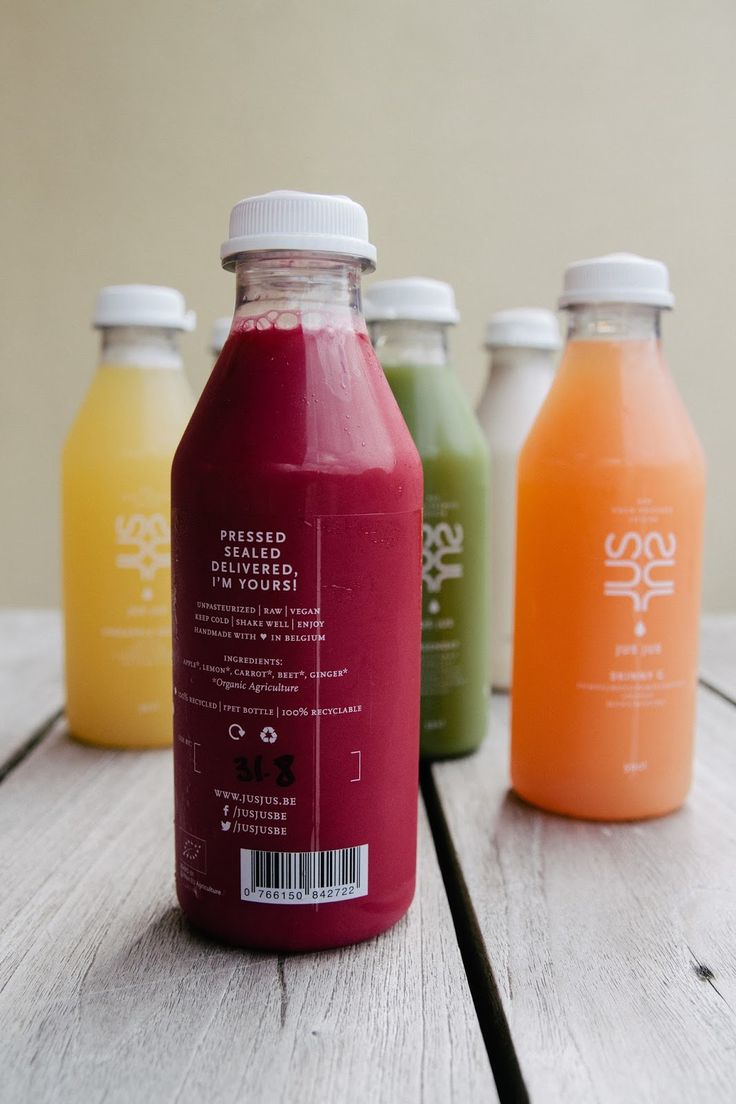 four bottles of juice sitting on top of a wooden table